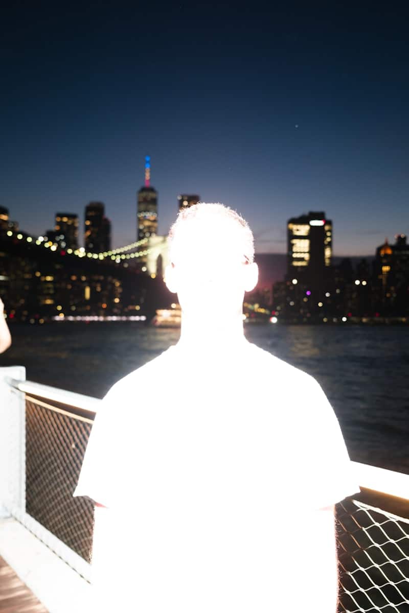 A person views a vibrant cityscape and bridge at night.