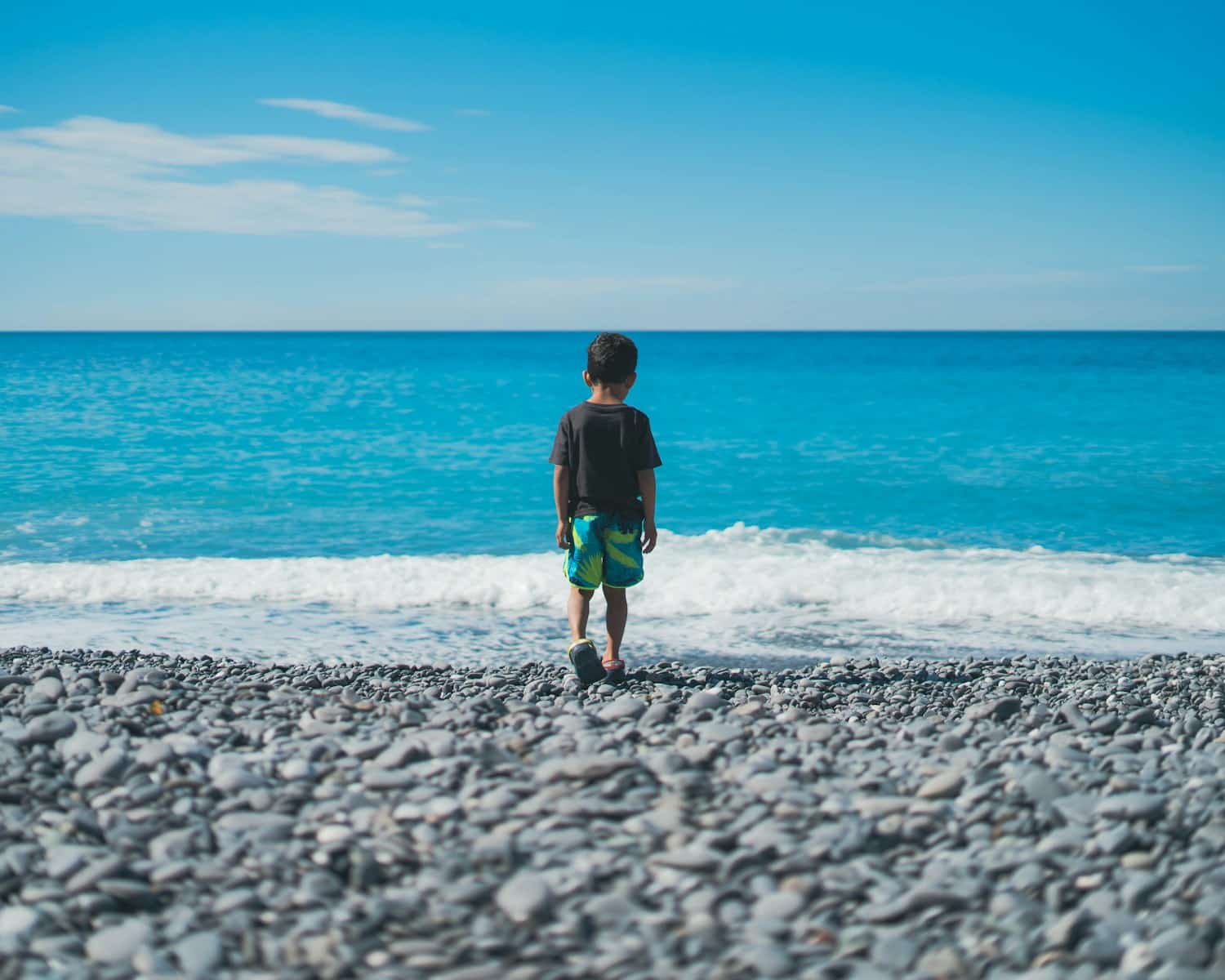 a person standing on a rocky beach near the ocean